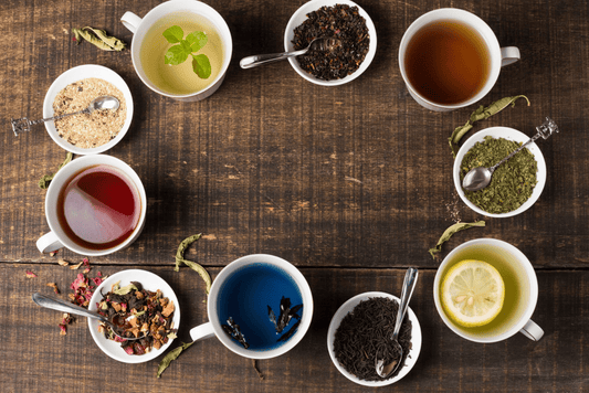 Différentes tasses de thés colorées posées en cercle sur une table en bois