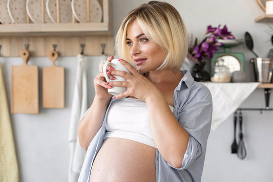 Femme enceinte tenant une tasse de thé dans les main